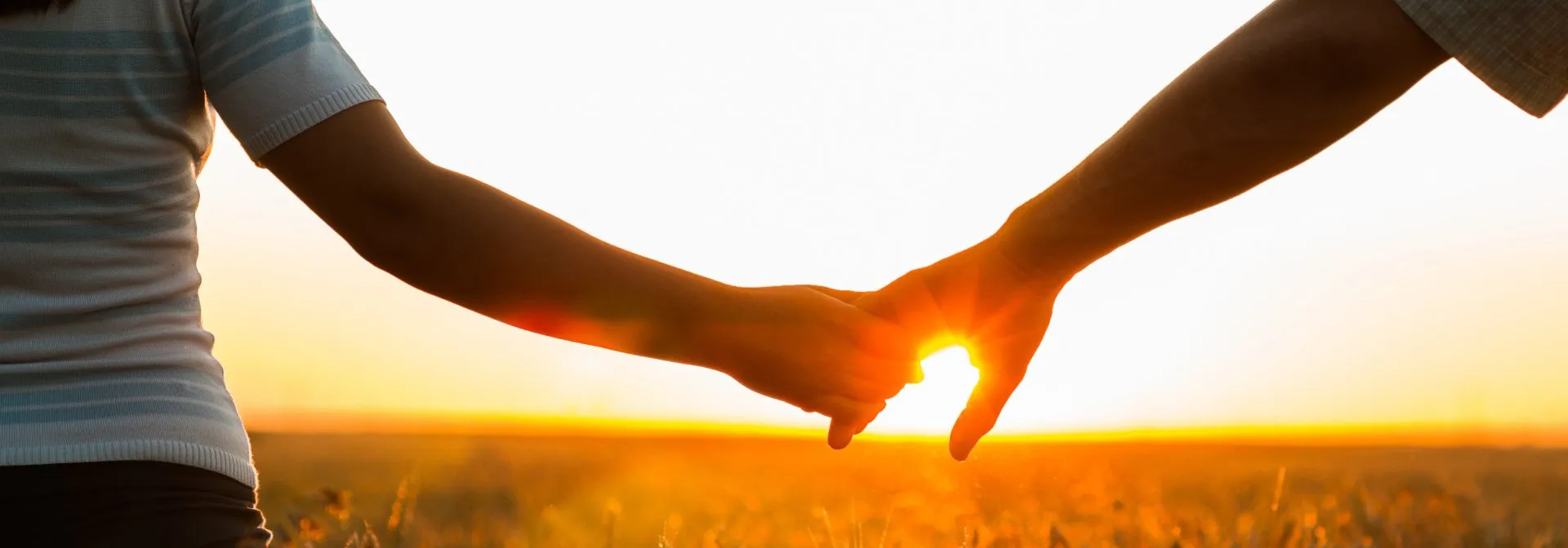 Ein Paar hält sich im Sonnenlicht an den Händen
